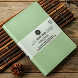 2026 Pistachio Green 18-month planner with white label on a wooden surface with bamboo and pine cone 