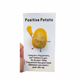 A collection of inspirational charms with humorous and supportive messages, including a blue bra charm, a potato with a sunburn, a taco, and a pickle. 