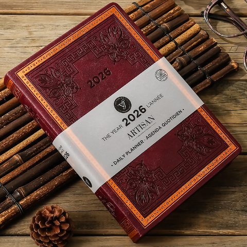 Red leather planner with '2026 Artisan' label on a wooden surface