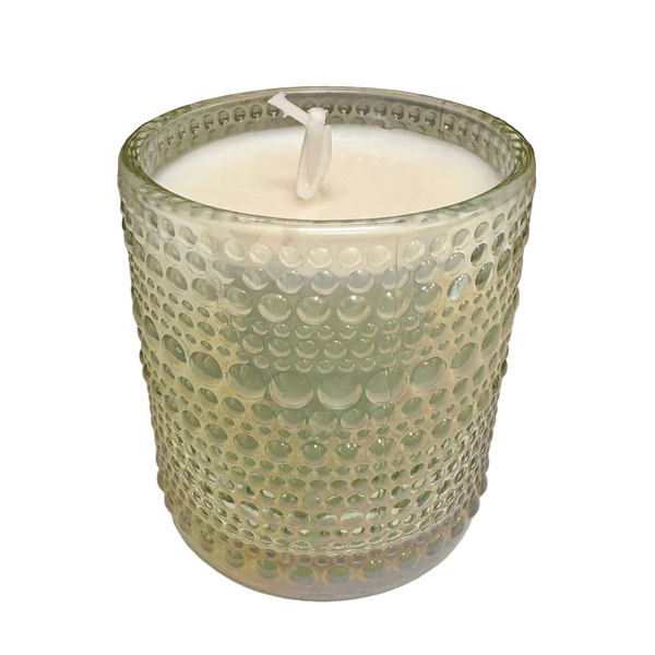 Candle in a textured glass holder on a plain surface
