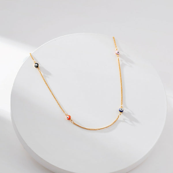Gold necklace with colorful evil eye beads on a white background