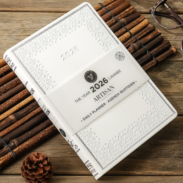 A white embossed 2026 daily planner on a wooden surface