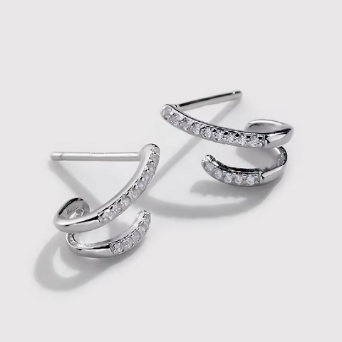 Pair of silver earrings with small diamonds on a light gray background