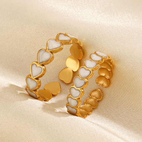 Pair of gold and white heart-shaped rings on a beige fabric background