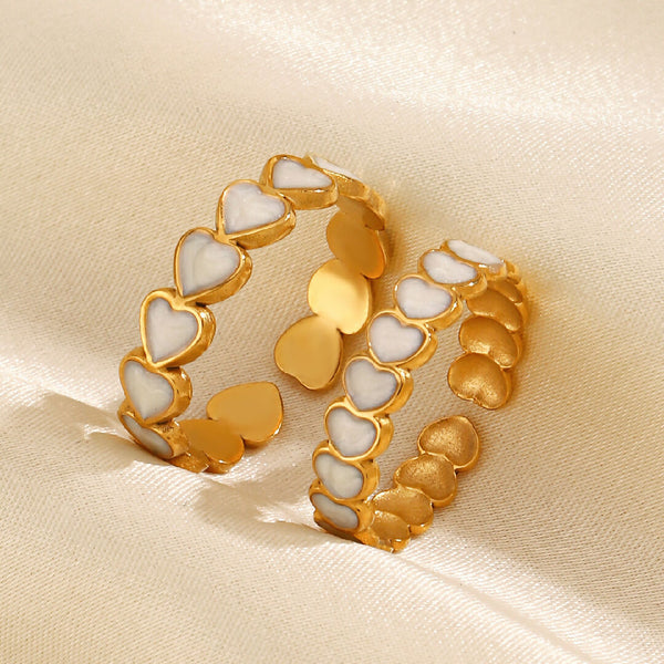 Pair of gold and white heart-shaped rings on a beige fabric background