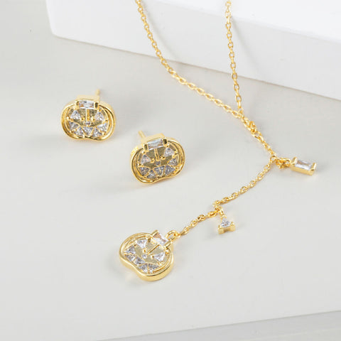 Gold jewelry set with necklace and earrings featuring pumpkin pendants on a light background
