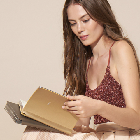 Woman reading a book with a soft, neutral background