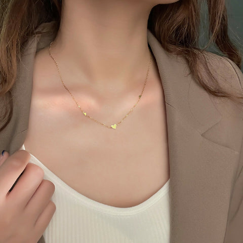 Gold necklace with heart pendants worn by a person